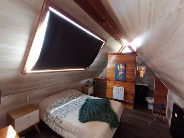 Interior de la casa de campo con cama y revestimiento de madera
